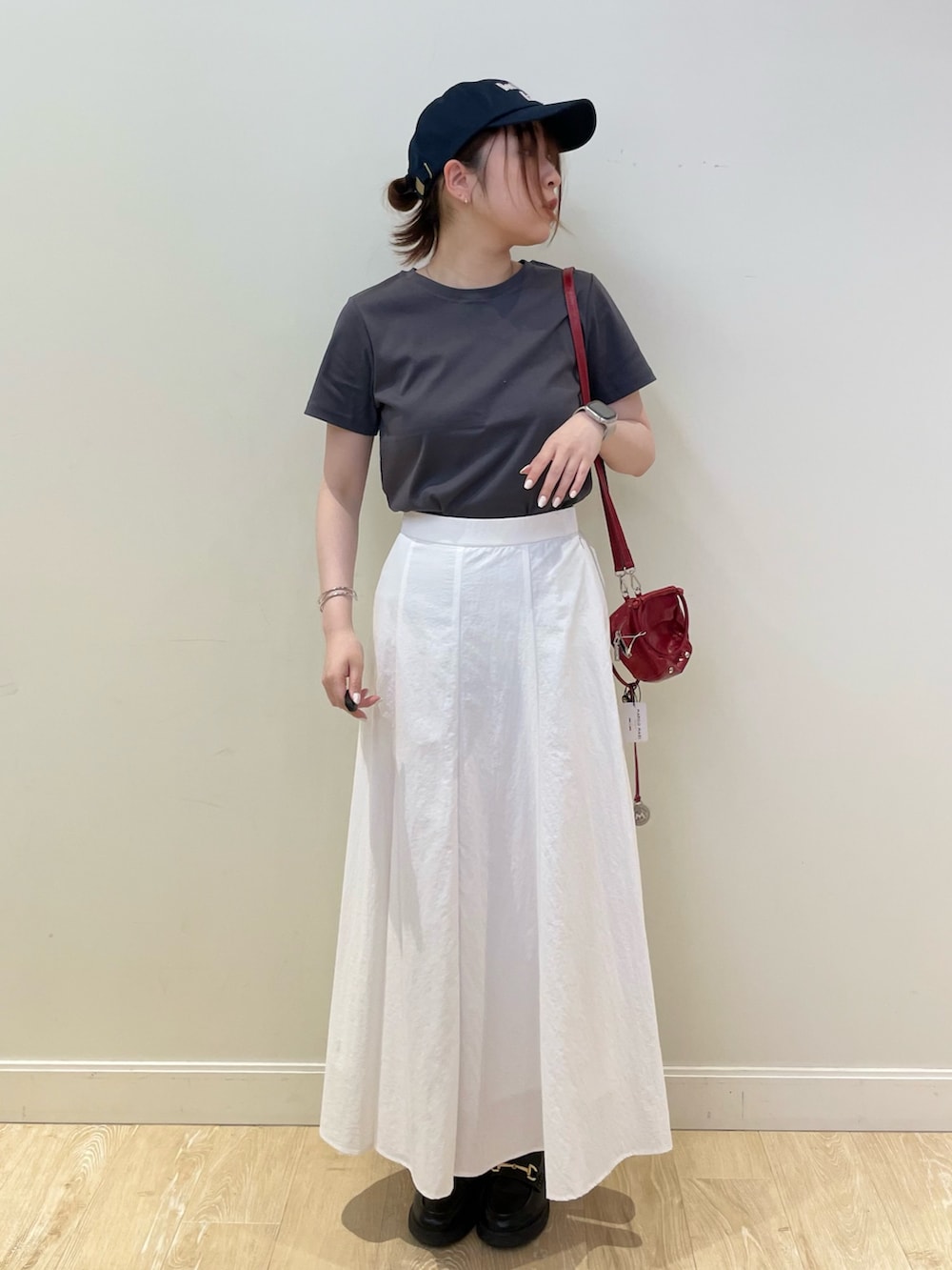 レッド系のショルダーバッグ、ホワイト系のスカート、グレー系のTシャツ/カットソーを着用したレディースの春コーディネートの3枚目の写真
