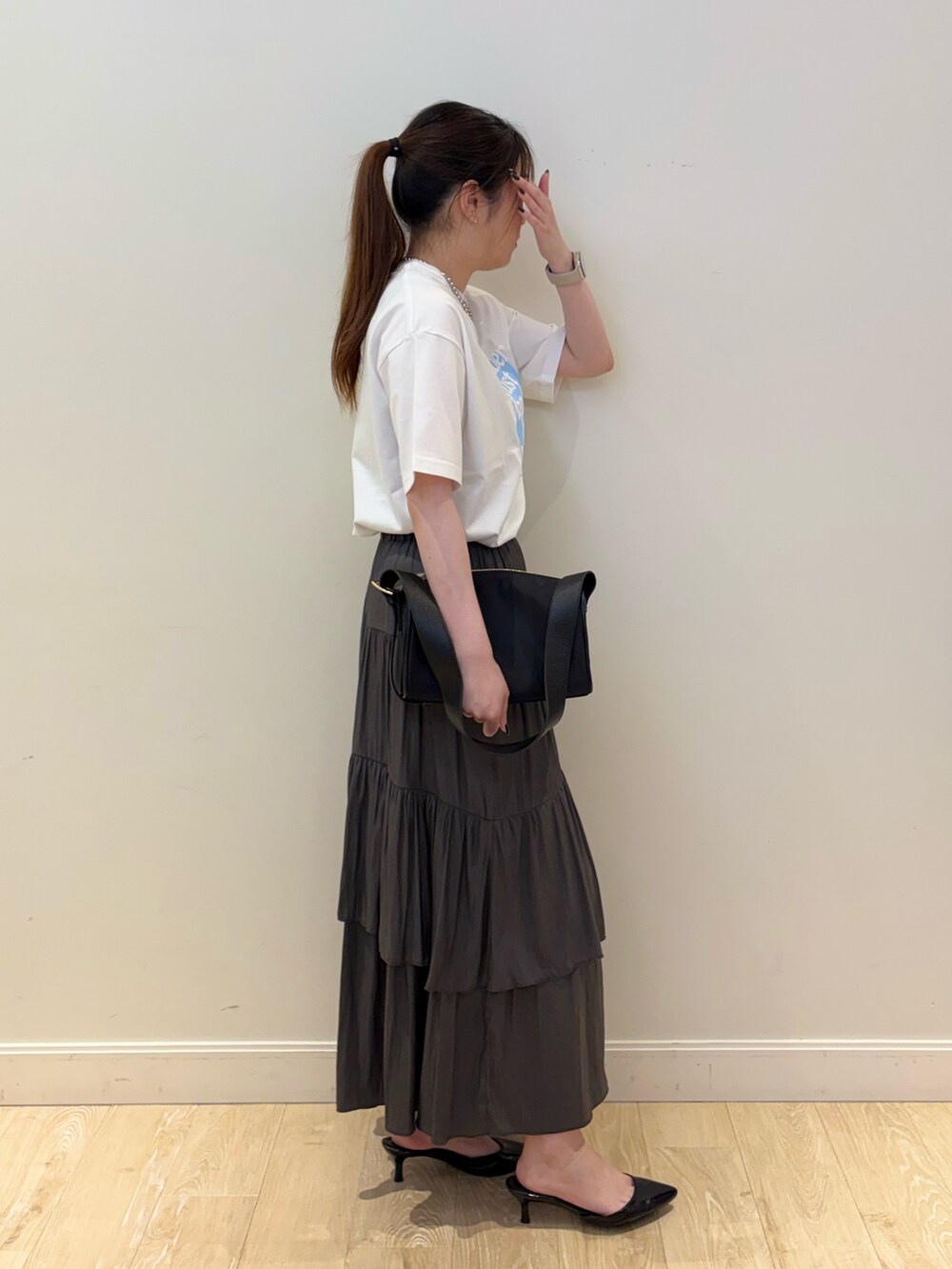 ブラック系のショルダーバッグ、グレー系のスカート、ホワイト系のTシャツ/カットソーを着用したレディースの夏コーディネートの2枚目の写真