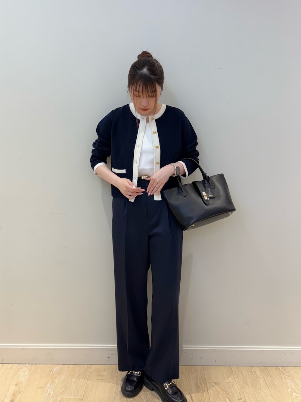 ブラック系のトートバッグ、ホワイト系のタンクトップ、ブルー系のカーディガン/ボレロを着用したレディースの春コーディネートの4枚目の写真