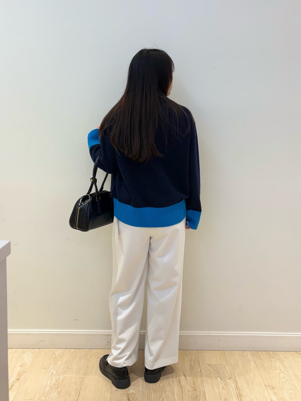 ブラック系のボストンバッグ、ホワイト系のその他パンツ、ブルー系のニット/セーターを着用したレディースの秋コーディネートの2枚目の写真