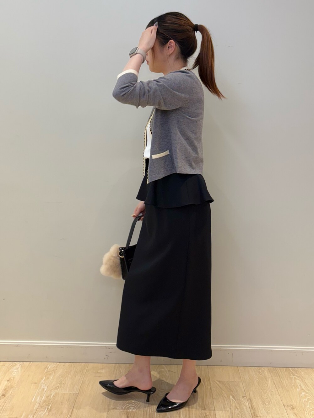 ブラック系のショルダーバッグ、ブラック系のスカート、ホワイト系のタンクトップを着用したレディースの秋コーディネートの3枚目の写真