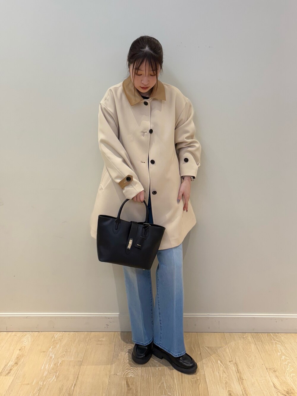 ブラック系のトートバッグ、ブルー系のデニムパンツ、ブラック系のニット/セーターを着用したレディースの冬コーディネートの4枚目の写真