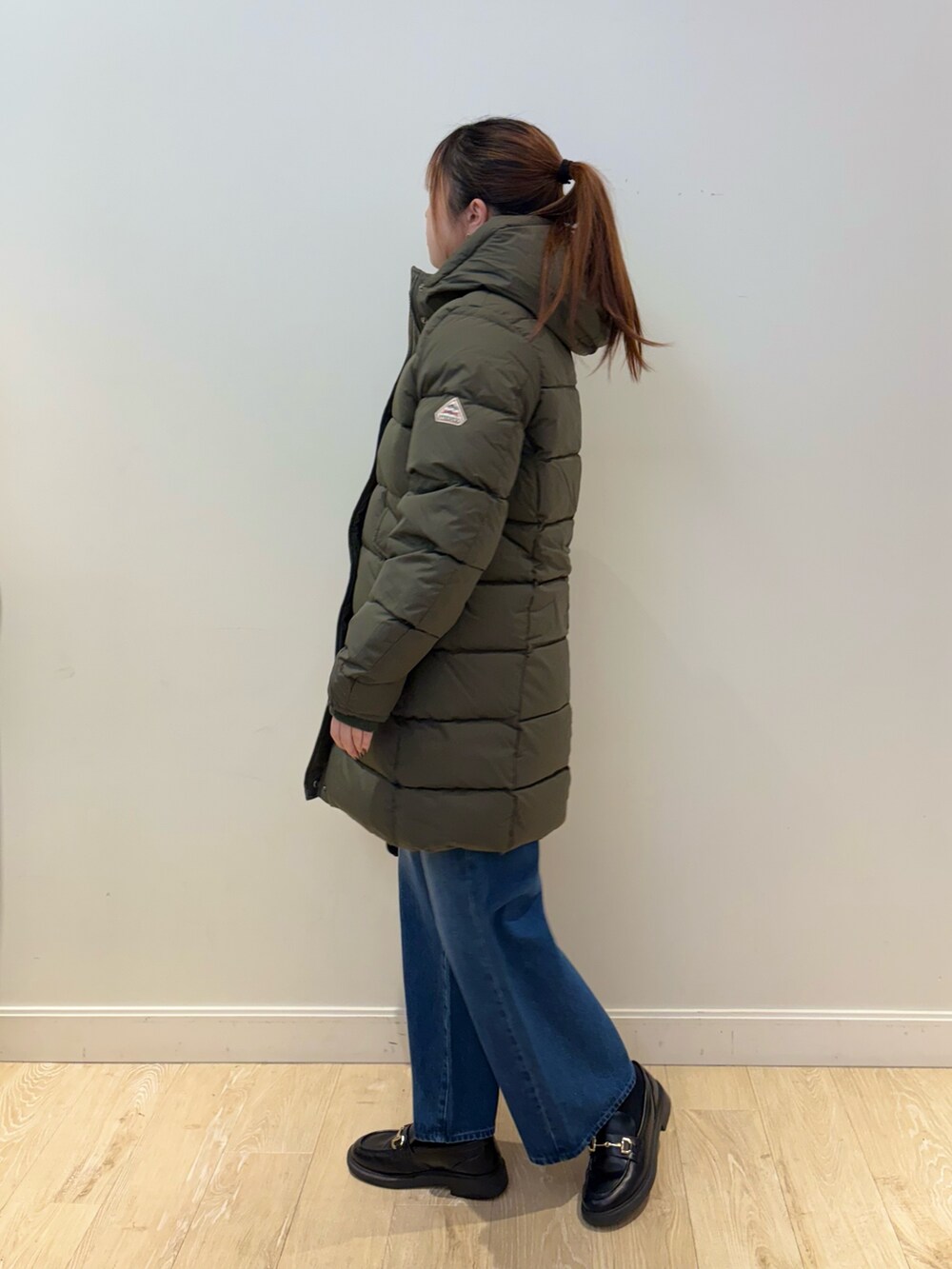 イエロー系のニット/セーター、ブルー系のデニムパンツ、ブラック系のショルダーバッグを着用したレディースの秋コーディネートの2枚目の写真