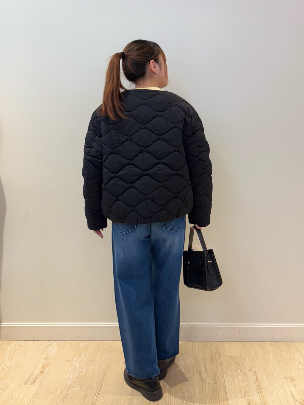 イエロー系のニット/セーター、ブルー系のデニムパンツ、ブラック系のショルダーバッグを着用したレディースの秋コーディネートの3枚目の写真