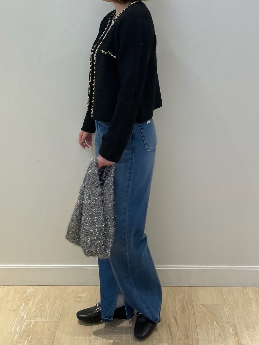 ブルー系のデニムパンツ、ゴールド系のニット/セーター、ブラック系のカーディガン/ボレロを着用したレディースの秋コーディネートの4枚目の写真