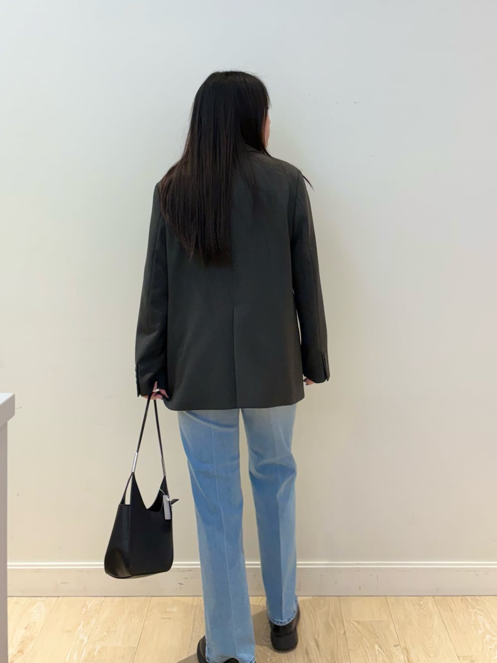 ブラック系のショルダーバッグ、ブルー系のデニムパンツ、ピンク系のTシャツ/カットソーを着用したレディースの秋コーディネートの2枚目の写真