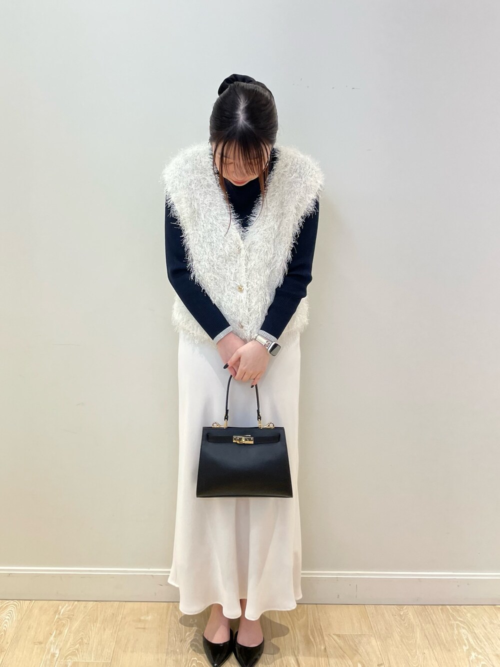 ホワイト系のベスト、ブルー系のニット/セーター、ホワイト系のスカートを着用したレディースの冬コーディネートの3枚目の写真