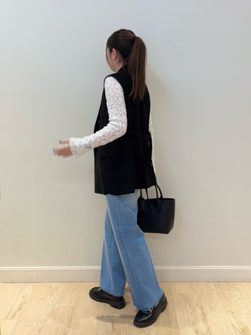 ブラック系のトートバッグ、ブルー系のデニムパンツ、ホワイト系のカーディガン/ボレロを着用したレディースの冬コーディネートの3枚目の写真