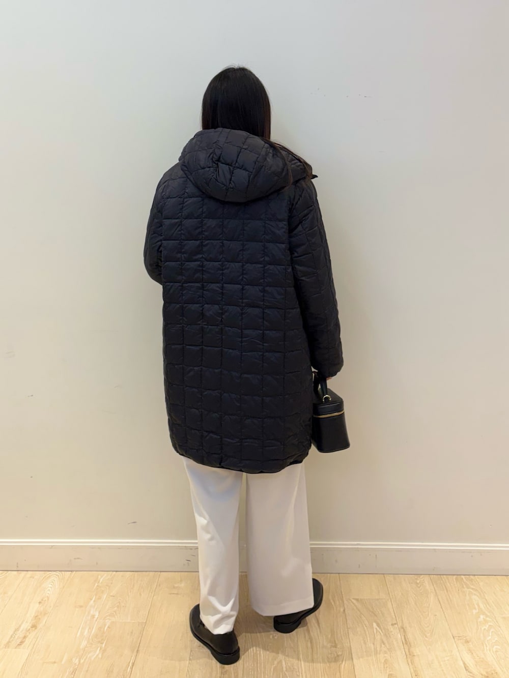 ブラック系のショルダーバッグ、レッド系のニット/セーター、ブラック系のダウンジャケット/コートを着用したレディースの秋コーディネートの2枚目の写真
