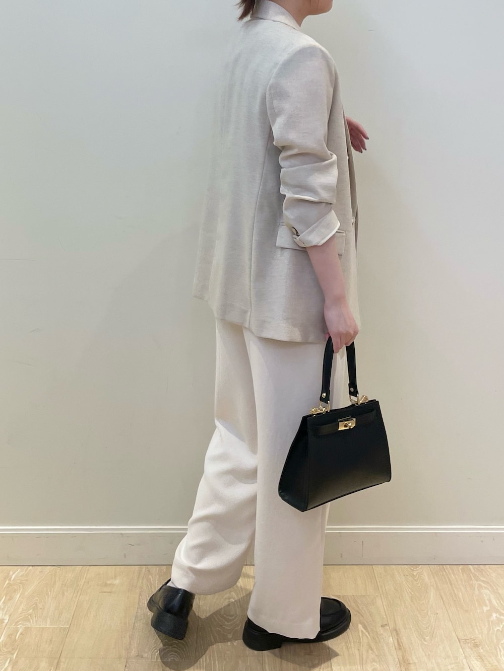 ブラック系のショルダーバッグ、ホワイト系のその他パンツ、ベージュ系のテーラードジャケットを着用したレディースの春コーディネートの2枚目の写真