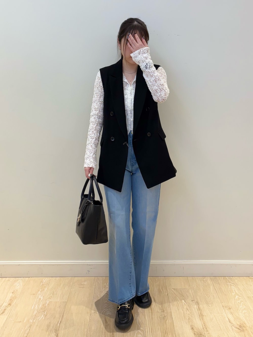 ブラック系のトートバッグ、ブルー系のデニムパンツ、ホワイト系のカーディガン/ボレロを着用したレディースの冬コーディネートの4枚目の写真