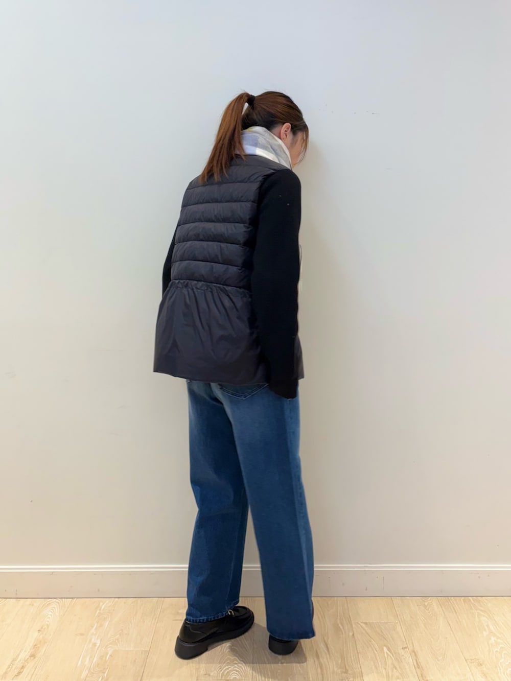 ブルー系のデニムパンツ、ブラック系のダウンジャケット/コート、ホワイト系のストール/ショールを着用したレディースの秋コーディネートの4枚目の写真