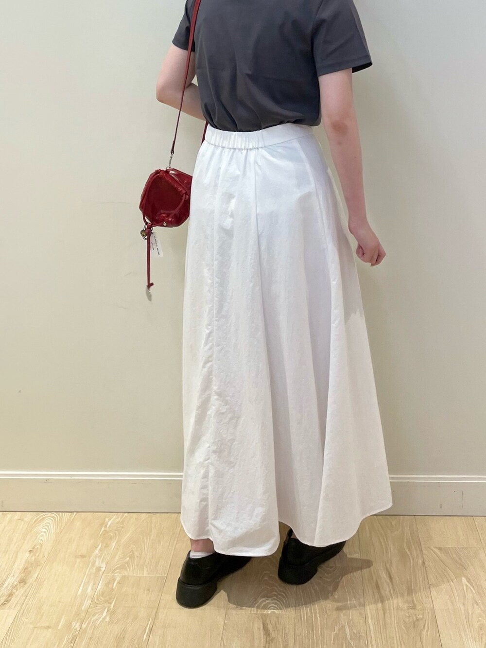 レッド系のショルダーバッグ、ホワイト系のスカート、グレー系のTシャツ/カットソーを着用したレディースの春コーディネートの4枚目の写真