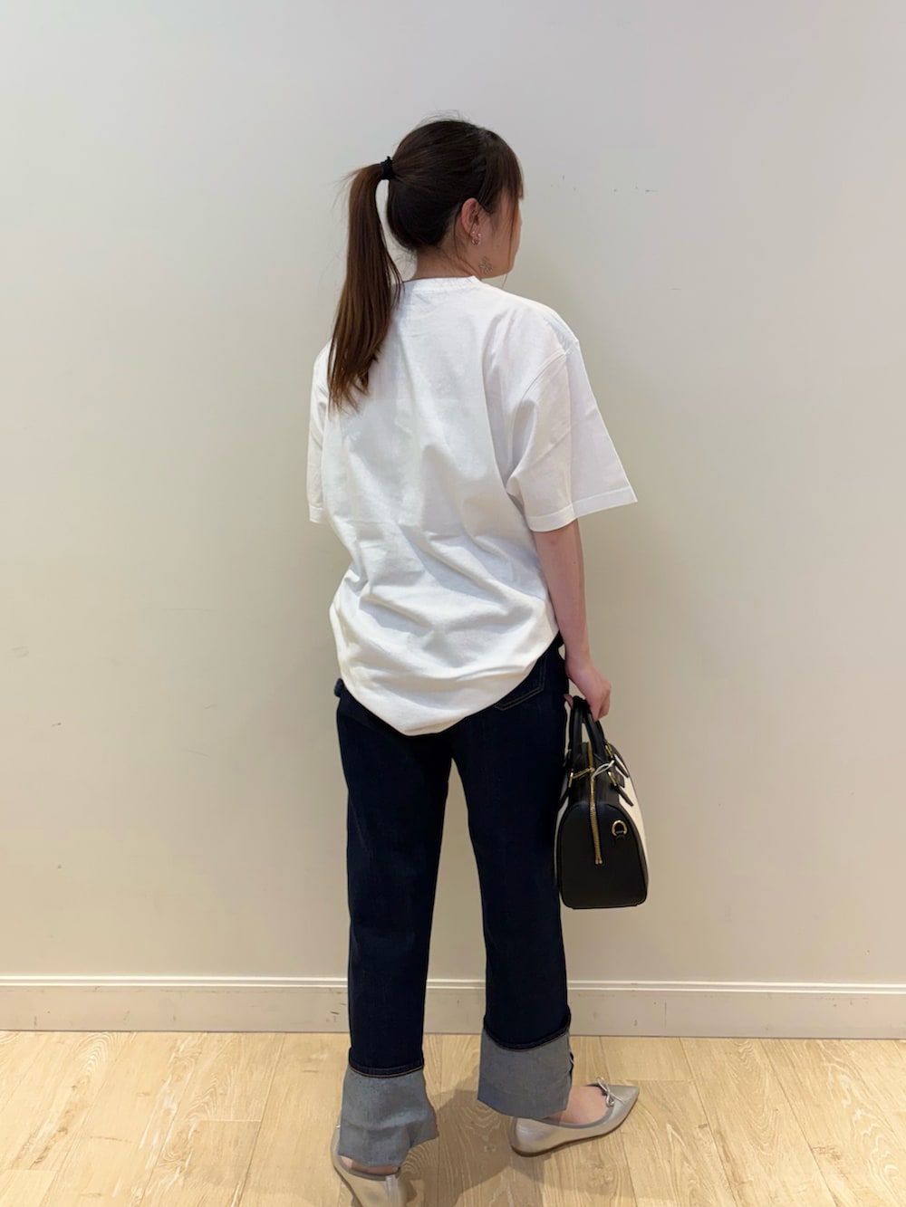 ブルー系のデニムパンツ、ブラック系のボストンバッグ、ホワイト系のTシャツ/カットソーを着用したレディースの春コーディネートの2枚目の写真