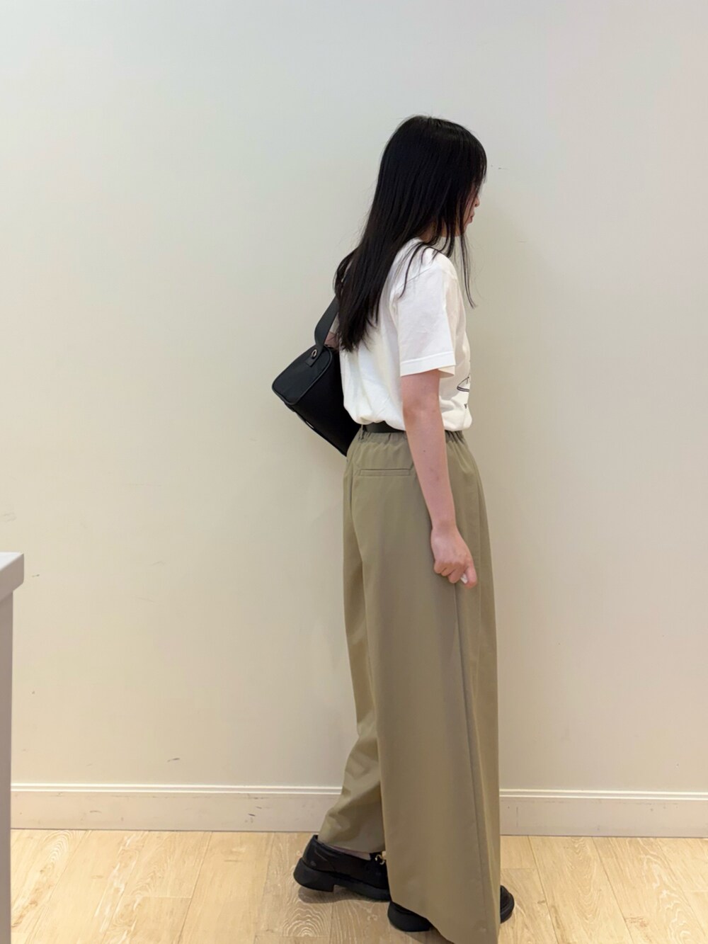 ブラック系のショルダーバッグ、ホワイト系のTシャツ/カットソー、ベージュ系のその他パンツを着用したレディースの夏コーディネートの2枚目の写真