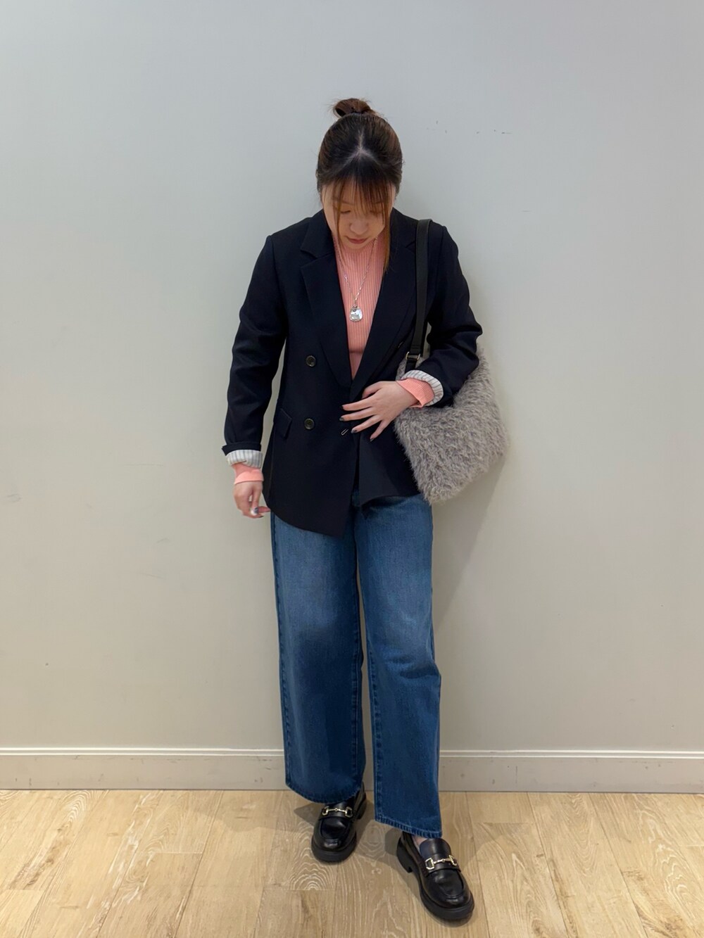 ブルー系のデニムパンツ、ベージュ系のショルダーバッグ、ピンク系のニット/セーターを着用したレディースの秋コーディネートの2枚目の写真