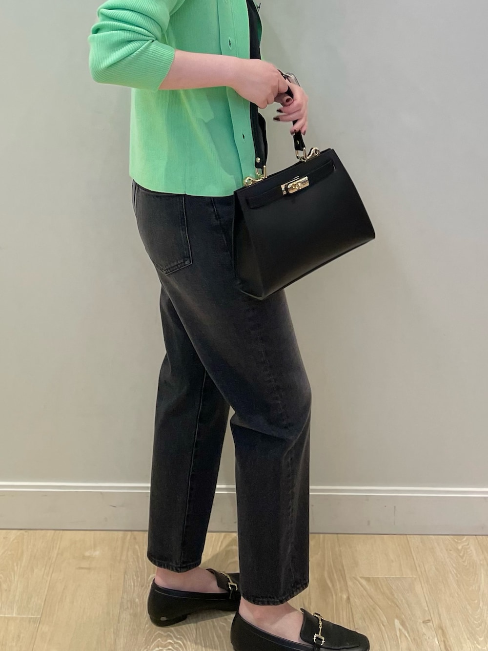 グリーン系のカーディガン/ボレロ、ブラック系のタンクトップ、ブラック系のデニムパンツを着用したレディースの冬コーディネートの4枚目の写真