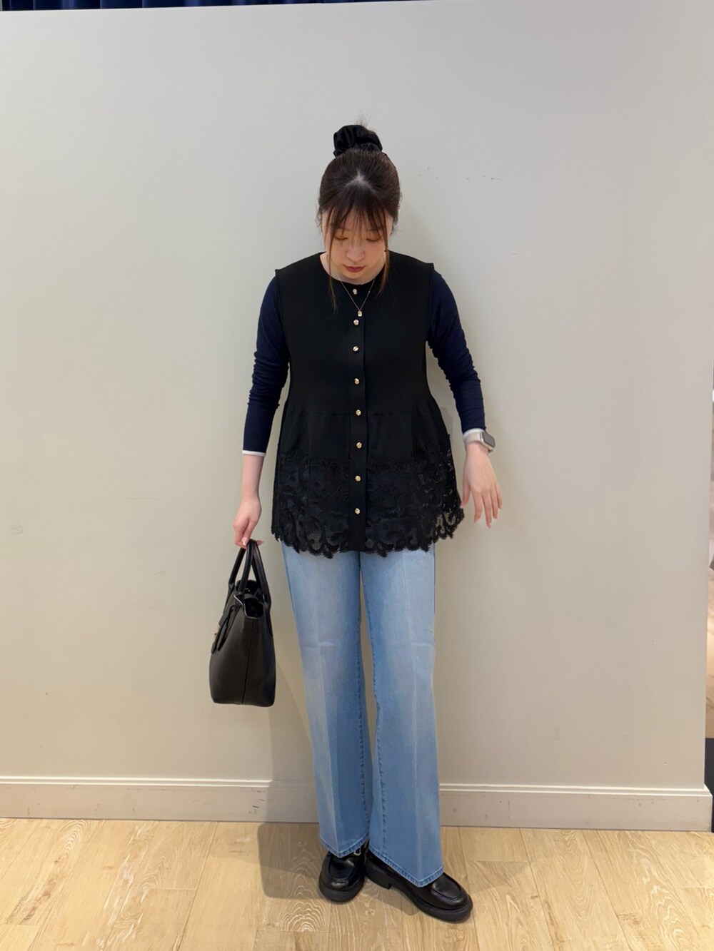 ブラック系のベスト、ブルー系のTシャツ/カットソー、ブラック系のトートバッグを着用したレディースの冬コーディネートの4枚目の写真