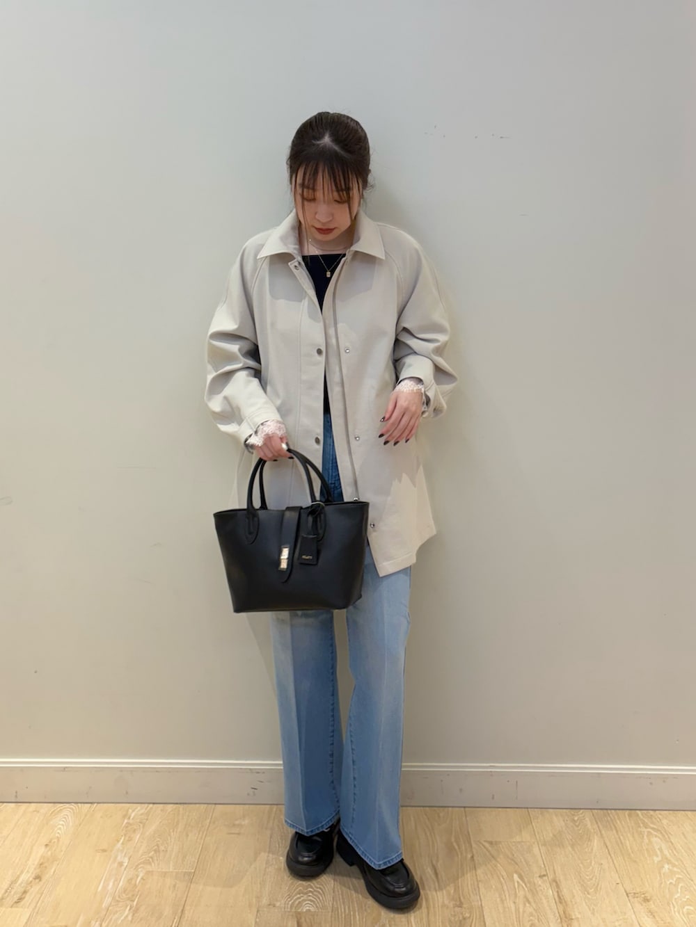 ブルー系のデニムパンツ、ブラック系のトートバッグ、ベージュ系のステンカラーコートを着用したレディースの冬コーディネートの4枚目の写真