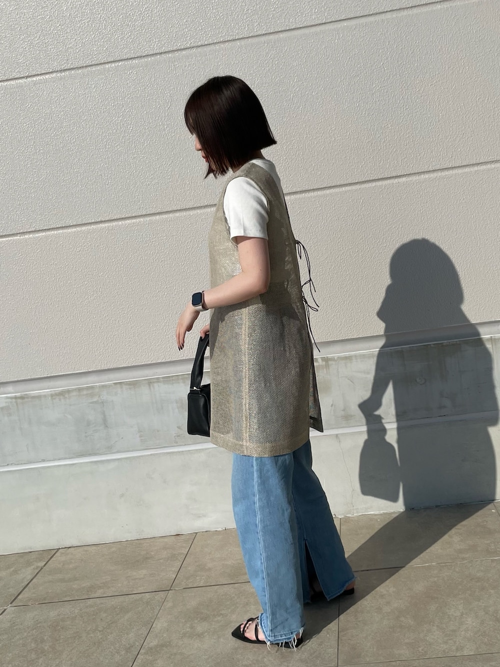 ブルー系のデニムパンツ、ブラック系のショルダーバッグ、ベージュ系のブルゾンを着用したレディースの夏コーディネートの2枚目の写真