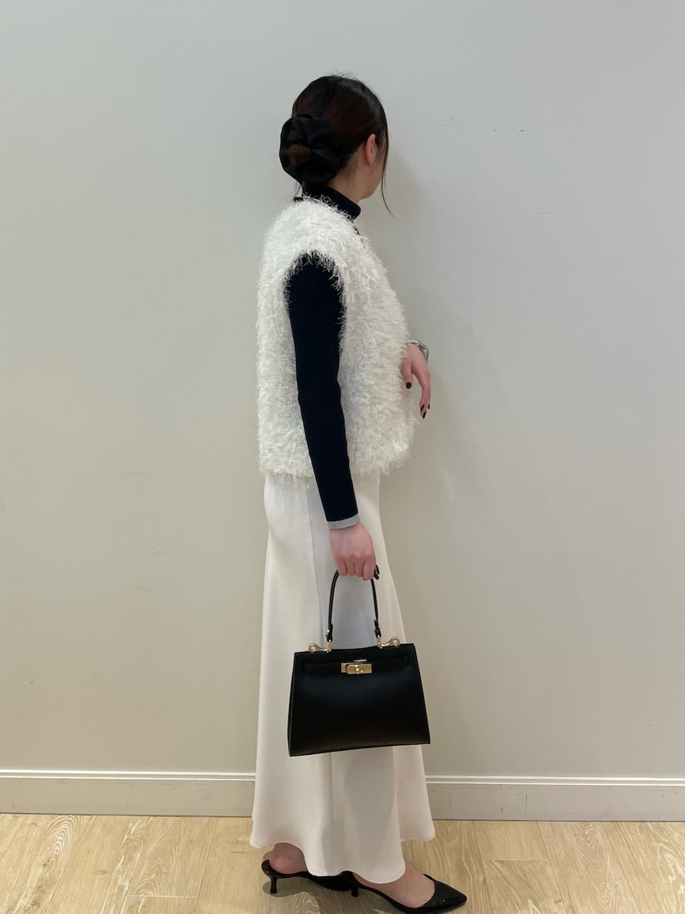 ホワイト系のベスト、ブルー系のニット/セーター、ホワイト系のスカートを着用したレディースの冬コーディネートの4枚目の写真