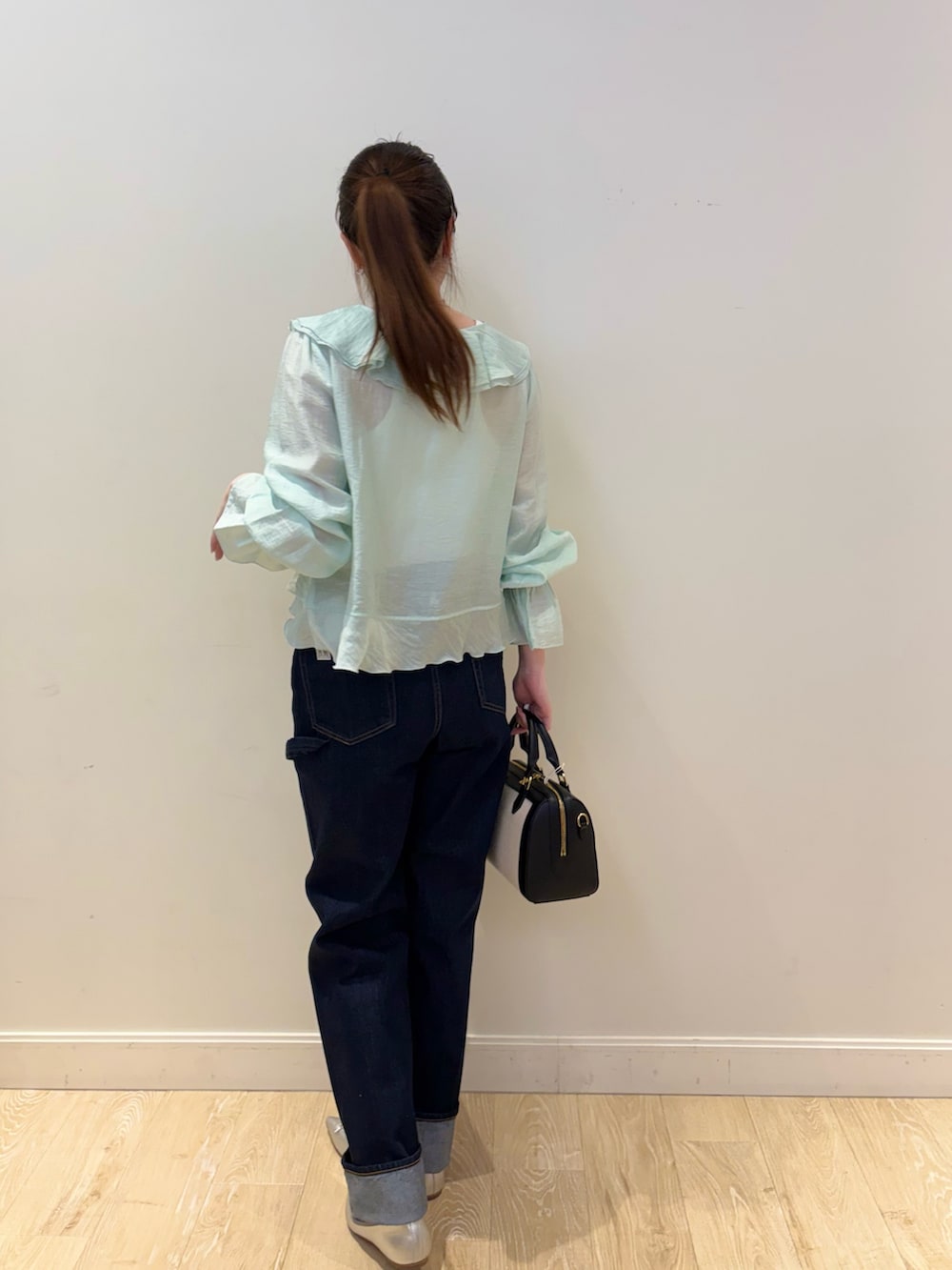 ホワイト系のタンクトップ、ブラック系のボストンバッグ、ブルー系のデニムパンツを着用したレディースの春コーディネートの2枚目の写真