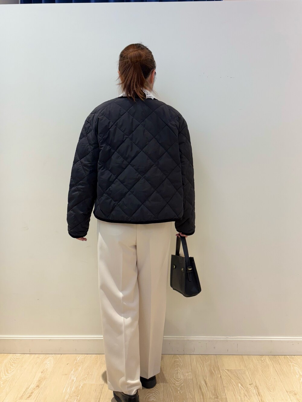 ブラック系のニット/セーター、ホワイト系のその他パンツ、ブラック系のショルダーバッグを着用したレディースの秋コーディネートの2枚目の写真