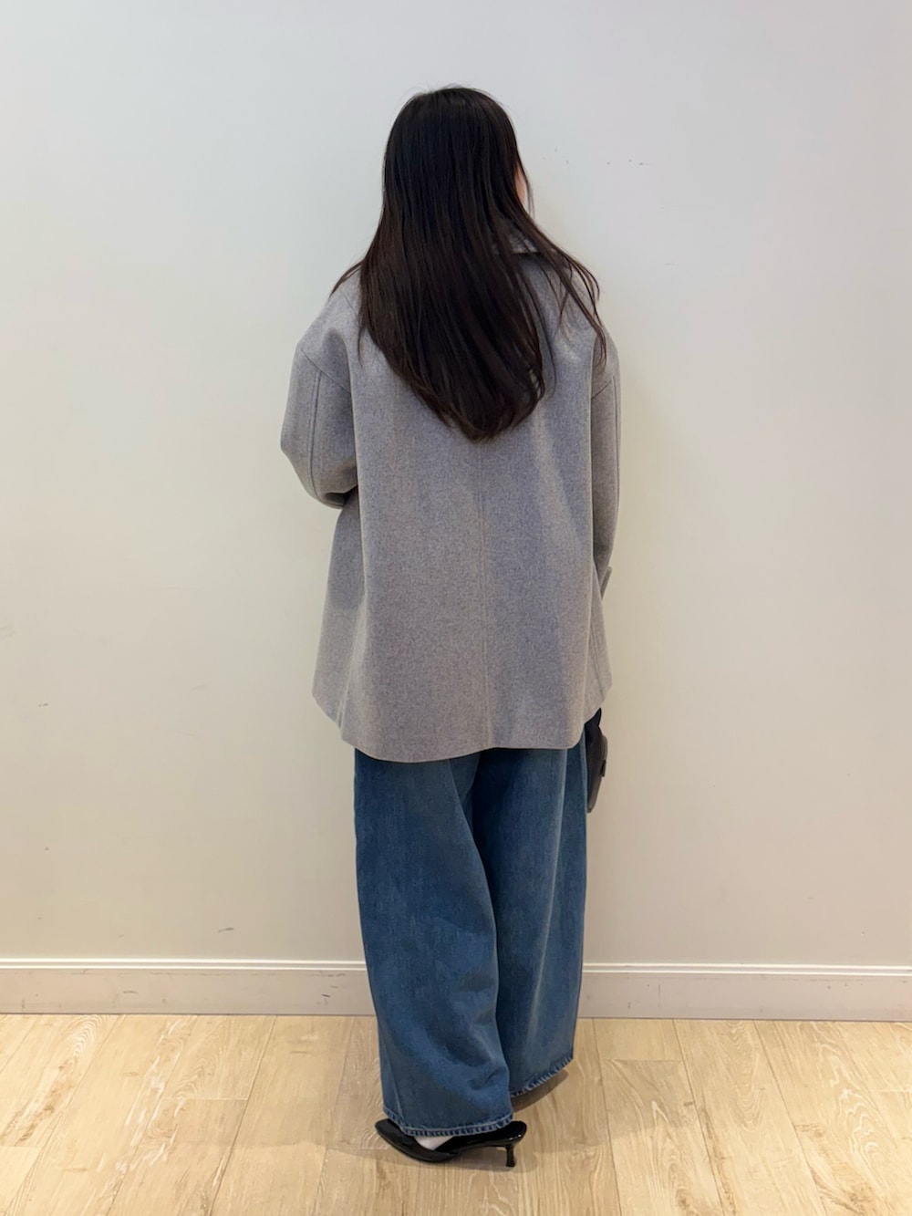 ブラック系のショルダーバッグ、ブルー系のデニムパンツ、グレー系のピーコートを着用したレディースの秋コーディネートの2枚目の写真