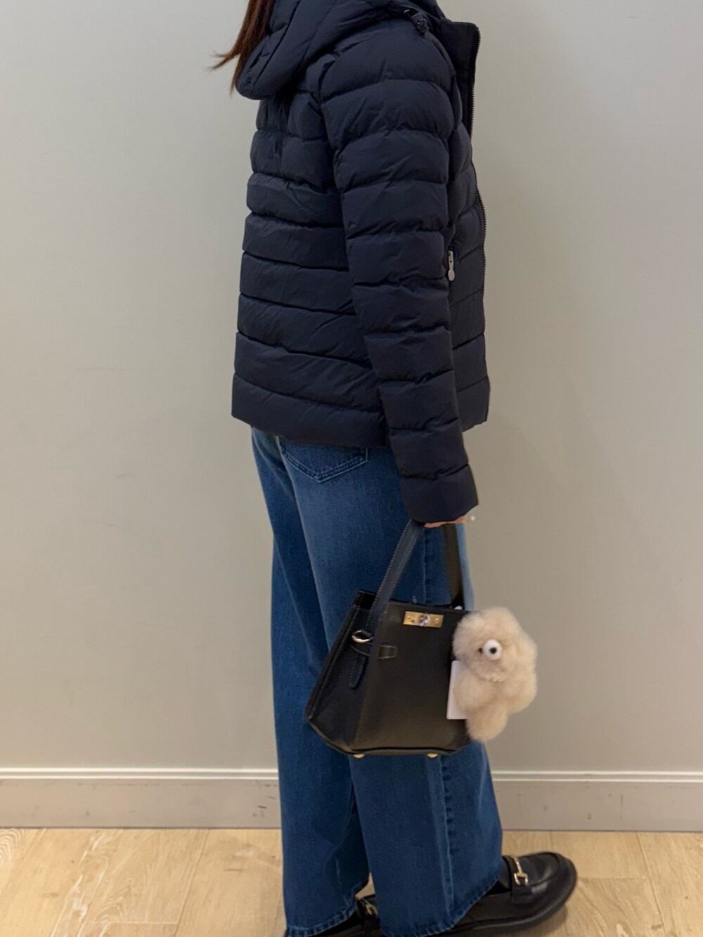 イエロー系のニット/セーター、ブルー系のデニムパンツ、ブラック系のショルダーバッグを着用したレディースの秋コーディネートの3枚目の写真