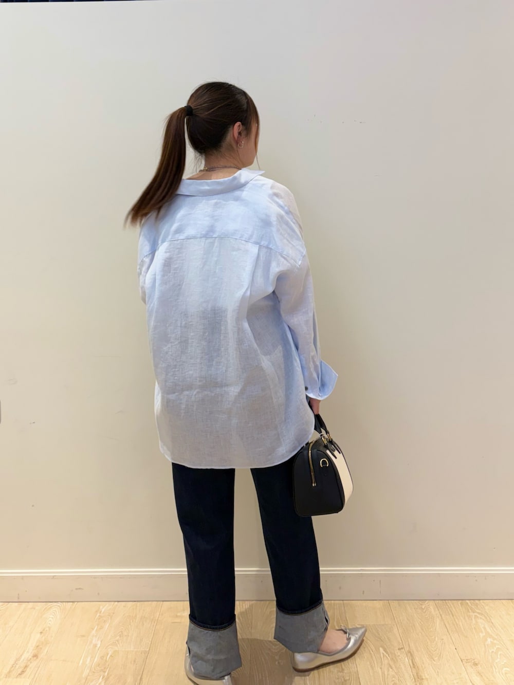 ブラック系のボストンバッグ、ブルー系のデニムパンツ、ホワイト系のタンクトップを着用したレディースの春コーディネートの2枚目の写真