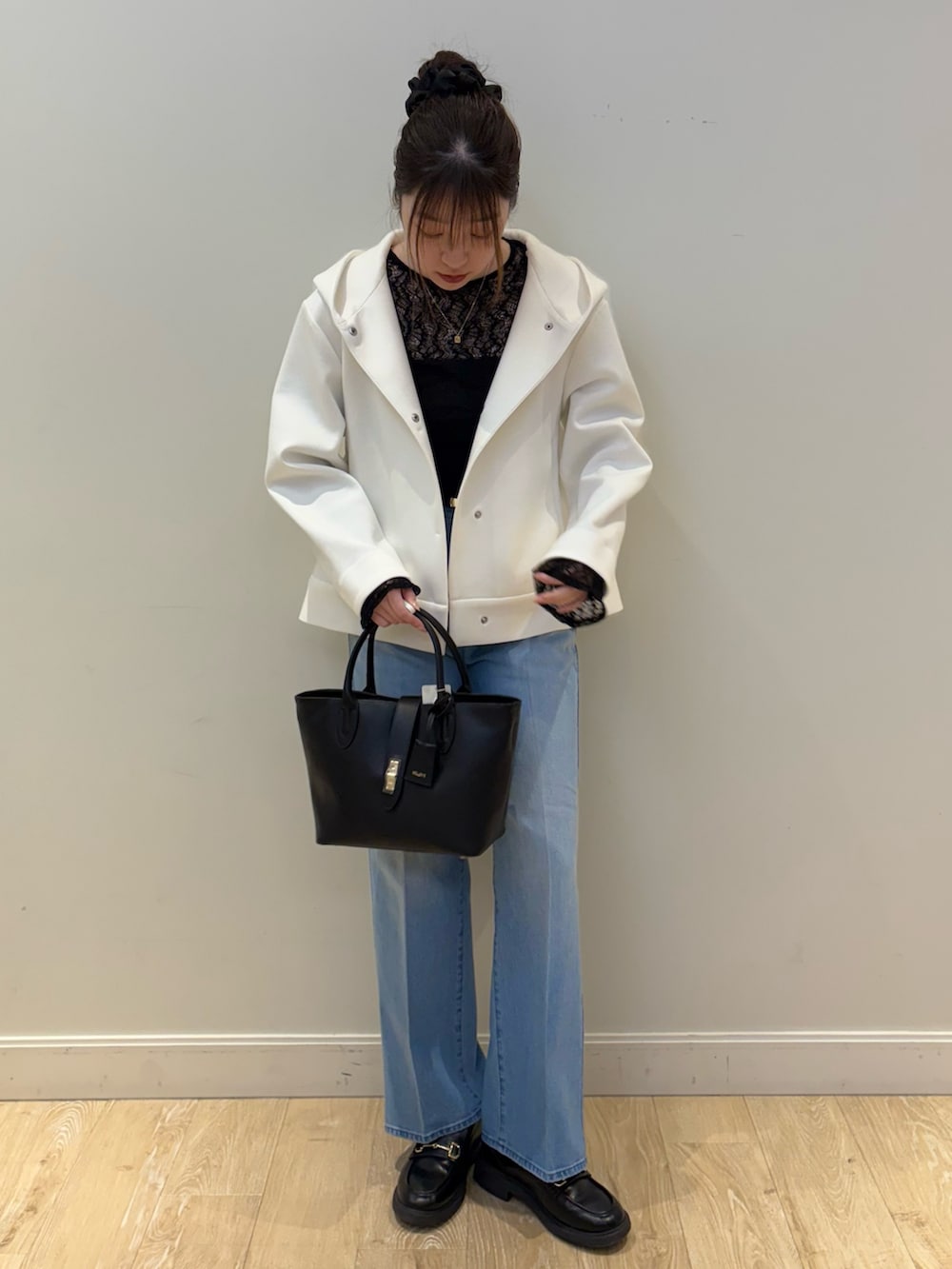ブラック系のトートバッグ、ブルー系のデニムパンツ、ホワイト系のブルゾンを着用したレディースの冬コーディネートの4枚目の写真