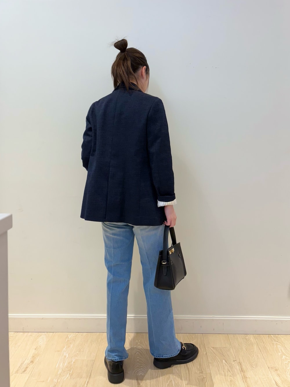 ブルー系のデニムパンツ、ブラック系のショルダーバッグ、ホワイト系のニット/セーターを着用したレディースの冬コーディネートの2枚目の写真