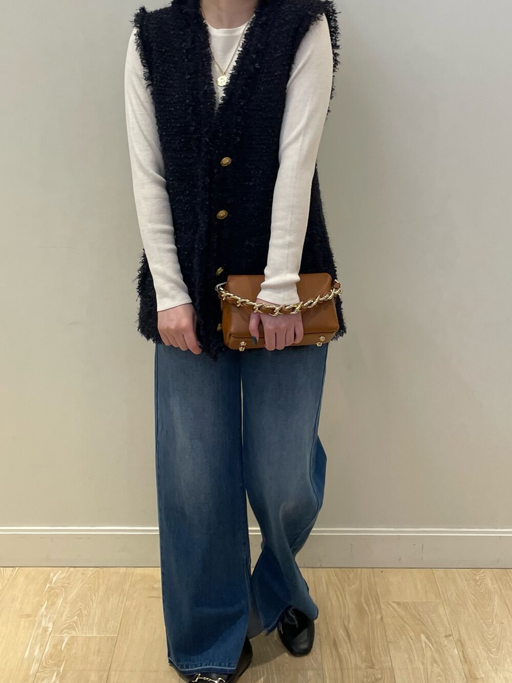 ブルー系のデニムパンツ、ホワイト系のニット/セーター、ブルー系のベストを着用したレディースの秋コーディネートの4枚目の写真