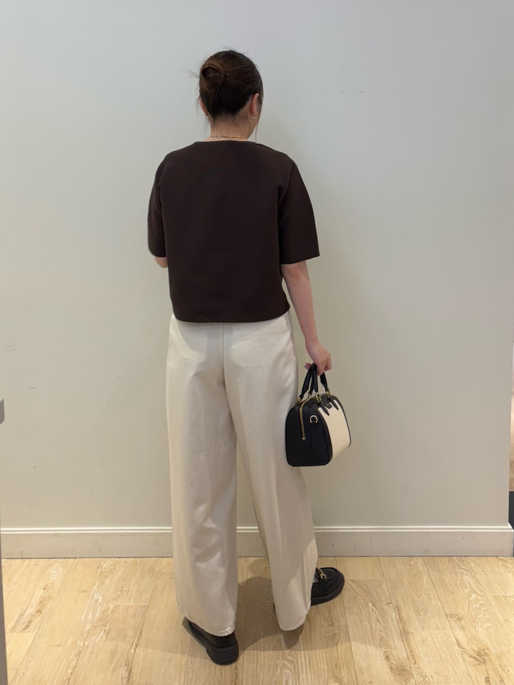 ブラック系のボストンバッグ、ブラウン系のニット/セーター、ホワイト系のその他パンツを着用したレディースの春コーディネートの2枚目の写真