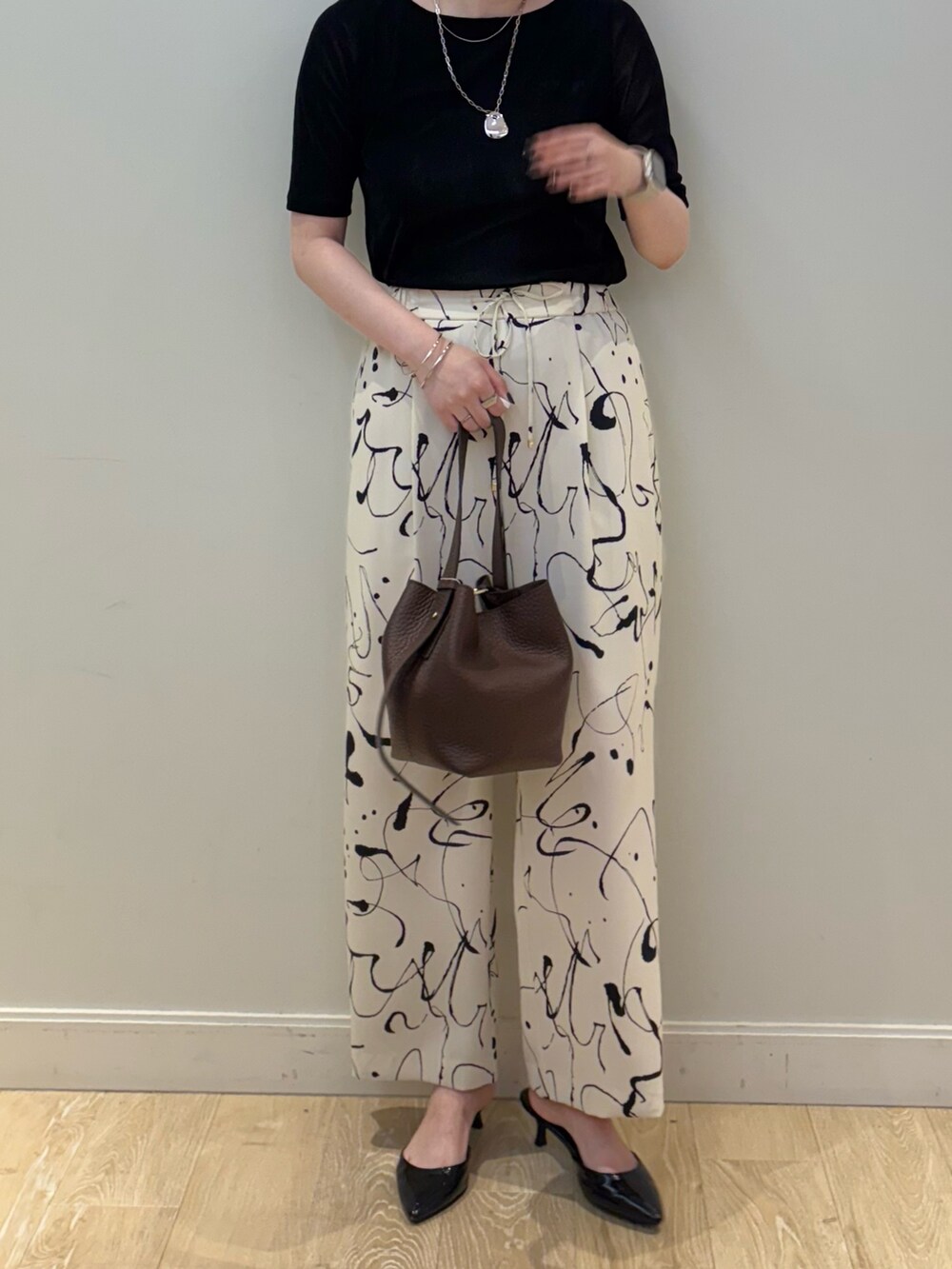 ブラウン系のショルダーバッグ、ホワイト系のその他パンツ、シルバー系のネックレスを着用したレディースの秋コーディネートの3枚目の写真