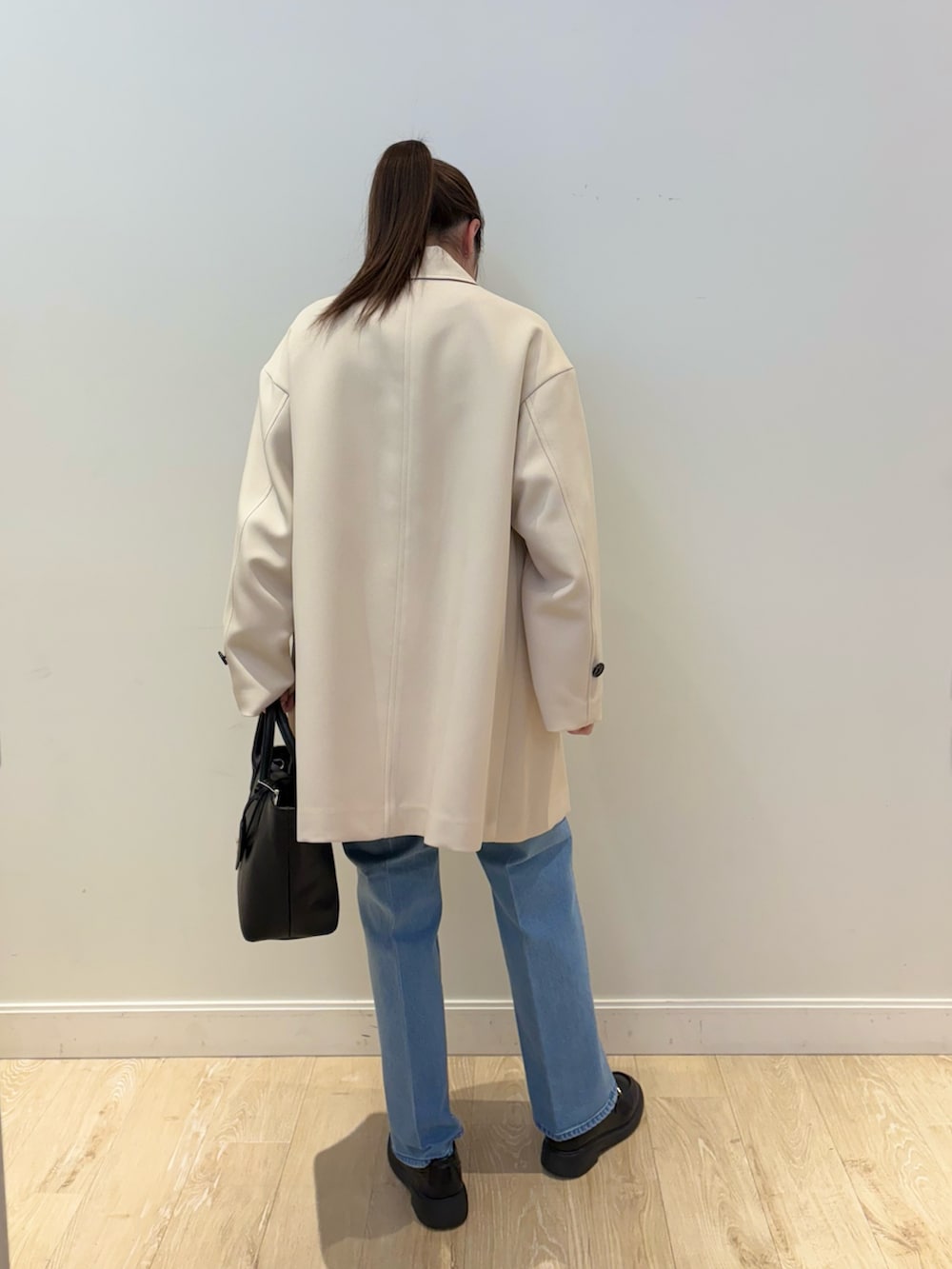 ブラック系のトートバッグ、ブルー系のデニムパンツ、ブラック系のニット/セーターを着用したレディースの冬コーディネートの3枚目の写真