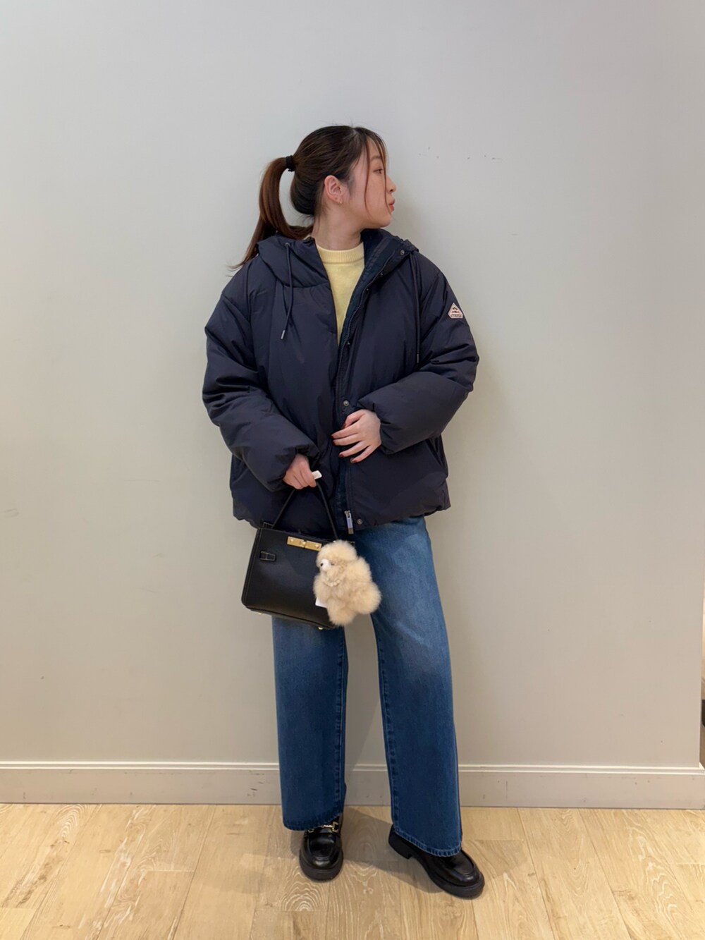 イエロー系のニット/セーター、ブルー系のデニムパンツ、ブラック系のショルダーバッグを着用したレディースの秋コーディネートの3枚目の写真