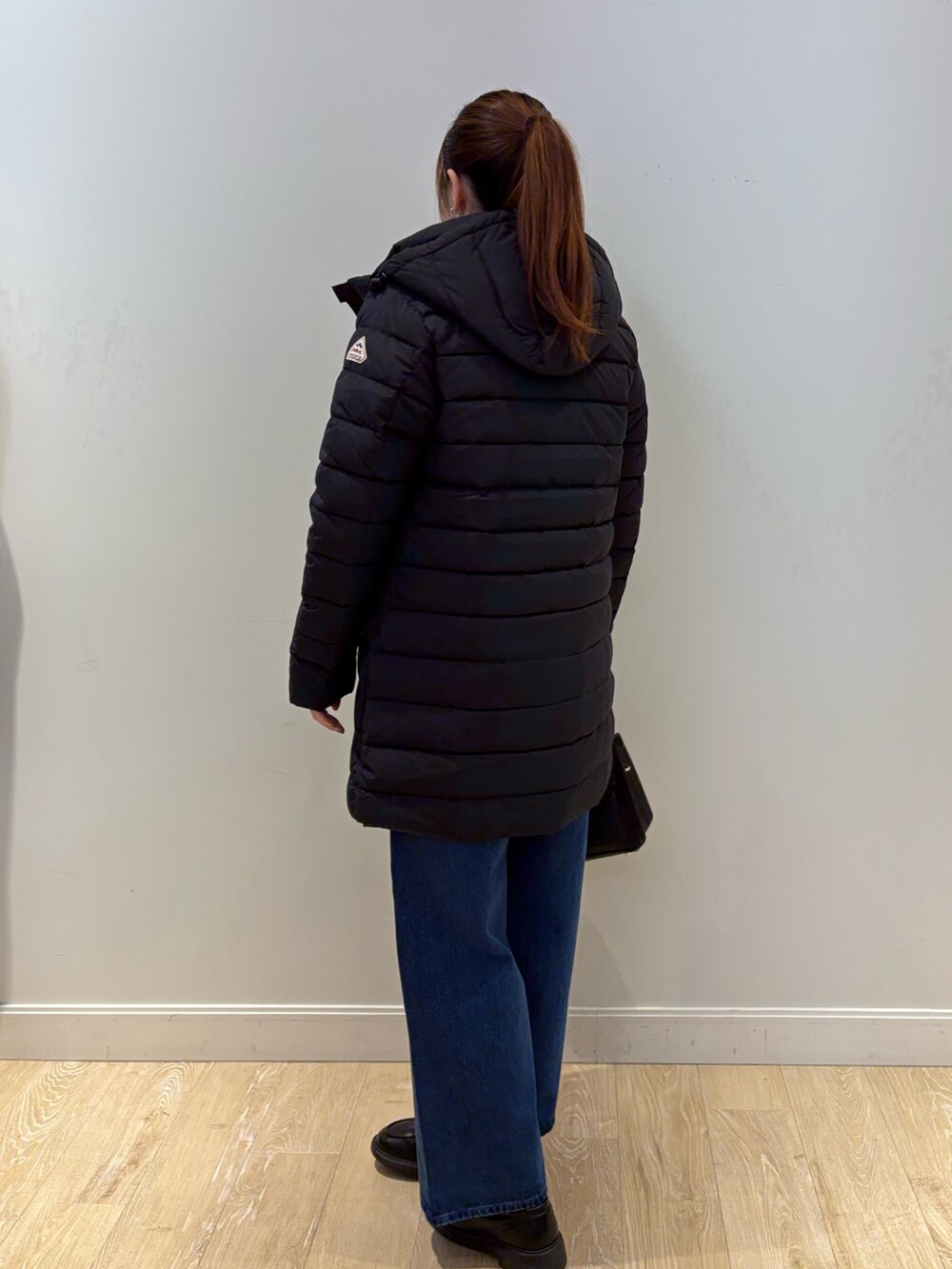 イエロー系のニット/セーター、ブラック系のショルダーバッグ、ブルー系のデニムパンツを着用したレディースの秋コーディネートの3枚目の写真