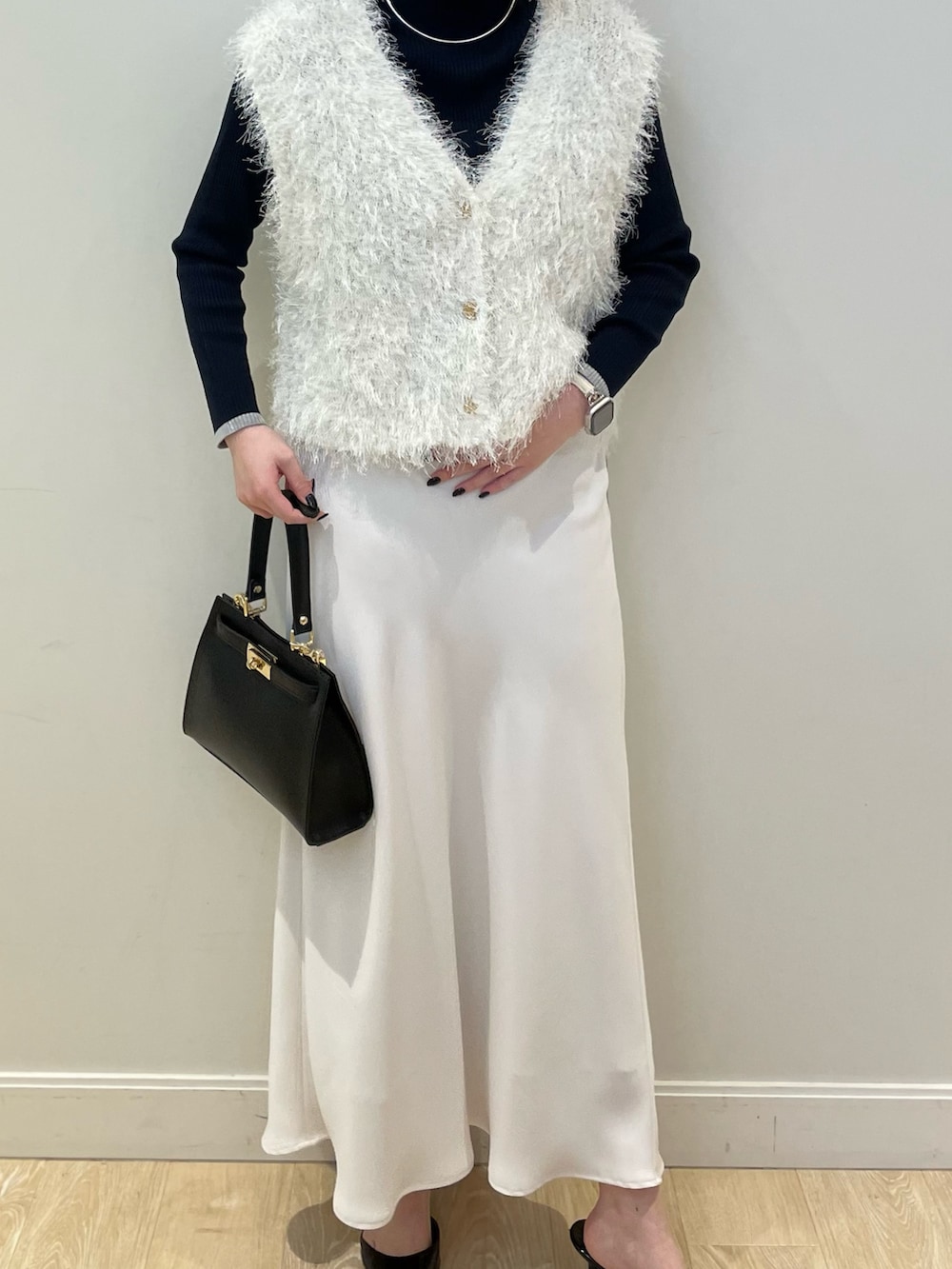 ホワイト系のベスト、ブルー系のニット/セーター、ホワイト系のスカートを着用したレディースの冬コーディネートの2枚目の写真