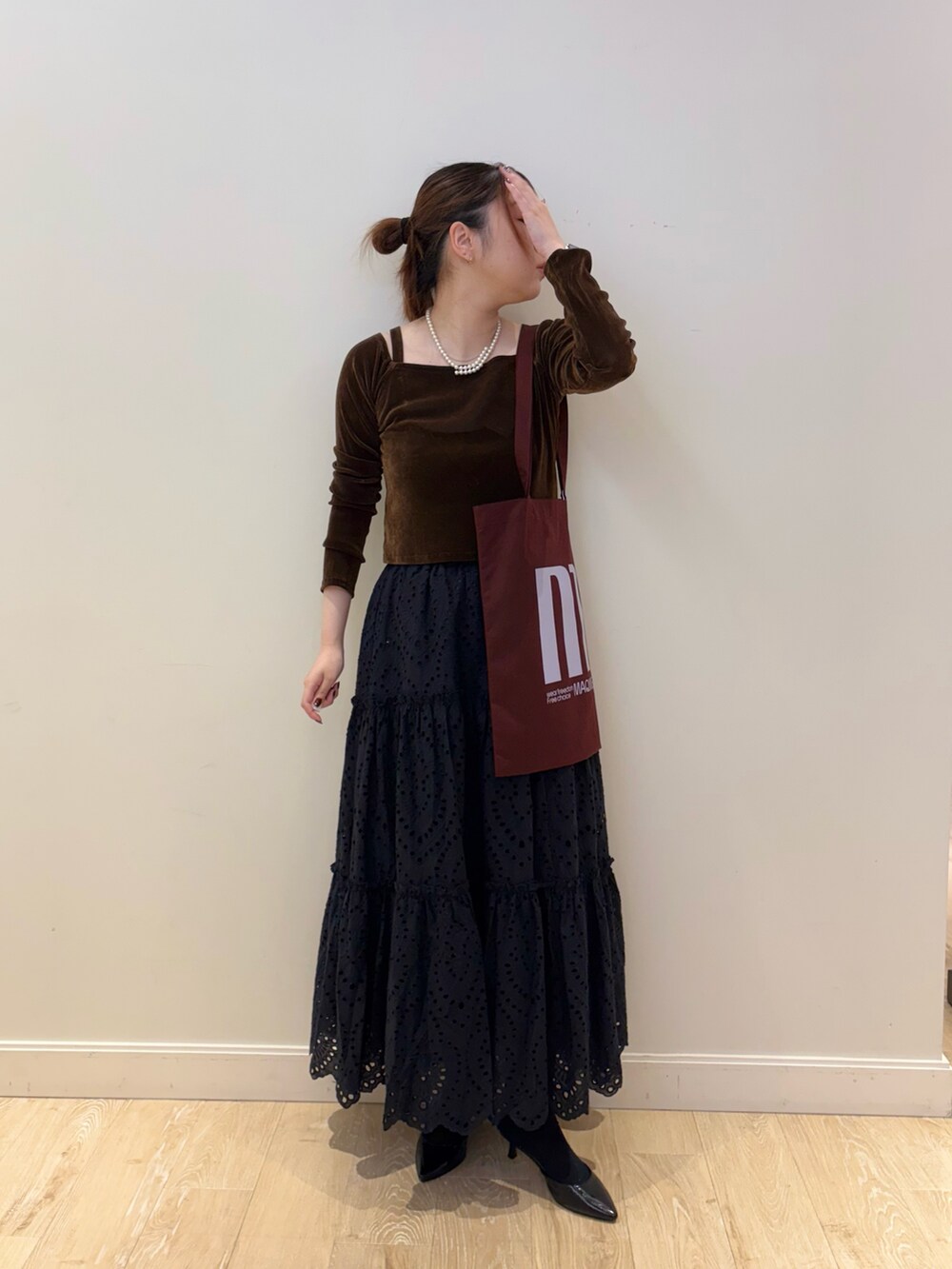 ブラック系のスカート、レッド系のトートバッグ、ブラウン系のTシャツ/カットソーを着用したレディースの秋コーディネートの3枚目の写真