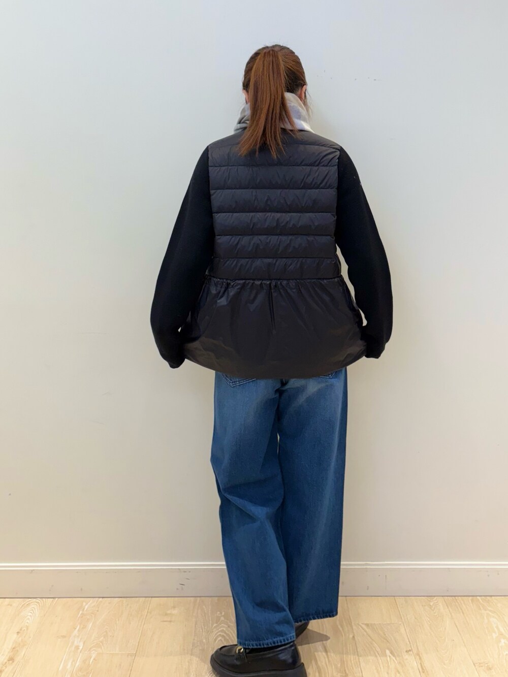 ブルー系のデニムパンツ、ブラック系のダウンジャケット/コート、ホワイト系のストール/ショールを着用したレディースの秋コーディネートの3枚目の写真