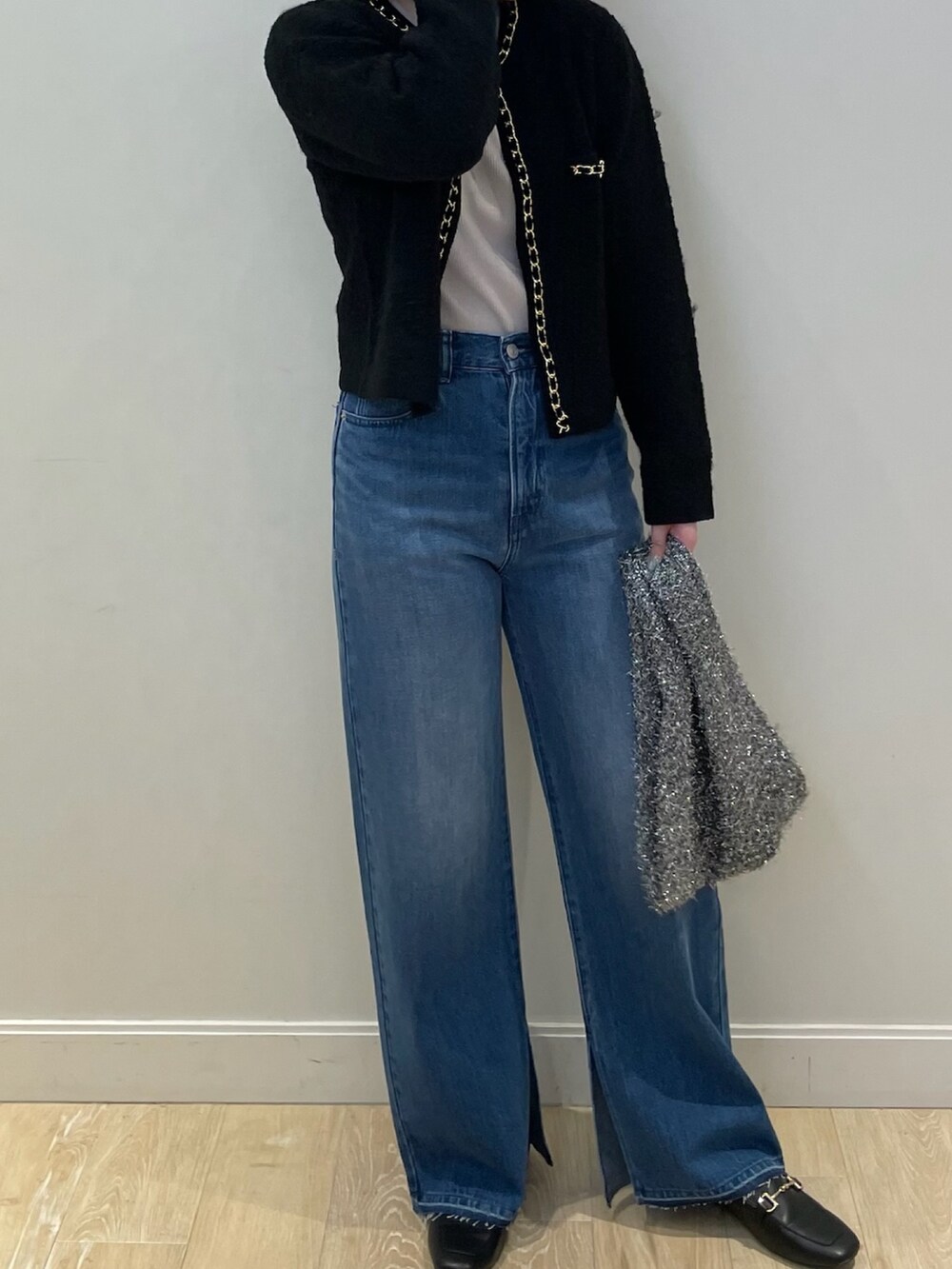 ブルー系のデニムパンツ、ゴールド系のニット/セーター、ブラック系のカーディガン/ボレロを着用したレディースの秋コーディネートの2枚目の写真