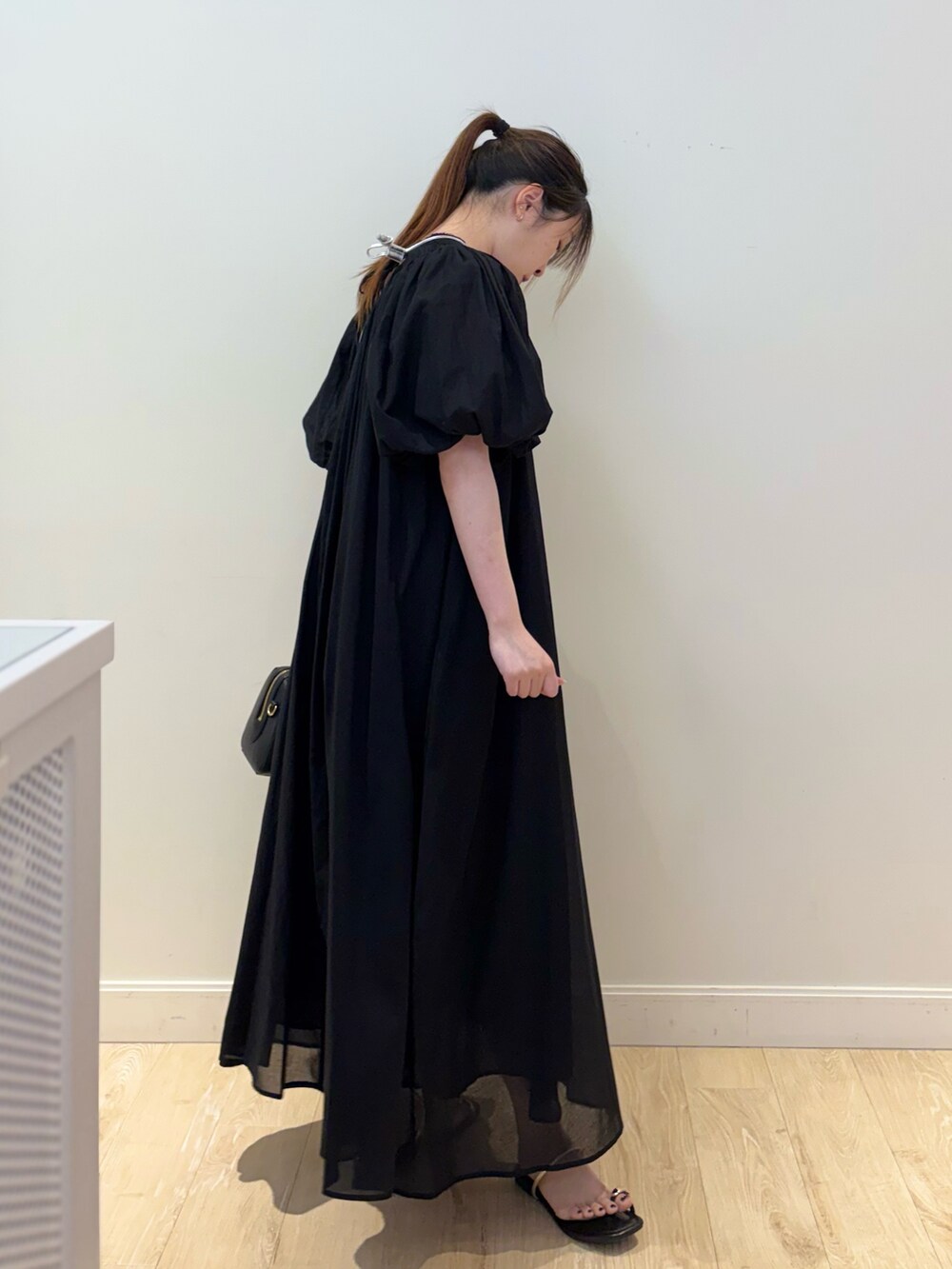 ブラック系のボストンバッグ、ブラック系のワンピース、シルバー系のチャームを着用したレディースの夏コーディネートの2枚目の写真
