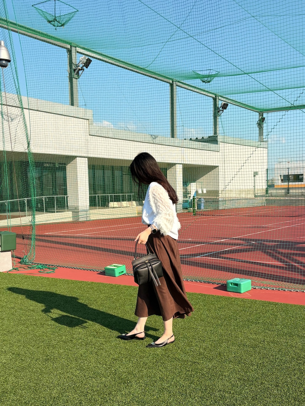 ブラック系のパンプス、ブラック系のショルダーバッグ、ブラウン系のスカートを着用したレディースの夏コーディネートの3枚目の写真