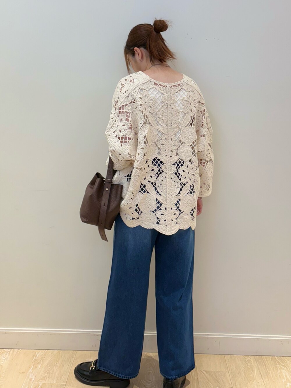 ブルー系のデニムパンツ、ブラウン系のショルダーバッグ、ホワイト系のタンクトップを着用したレディースの夏コーディネートの2枚目の写真