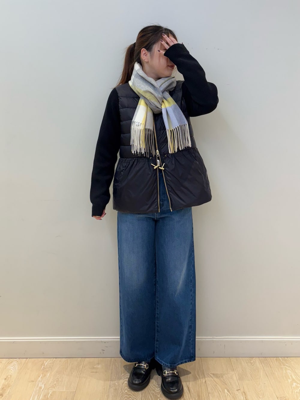 ブルー系のデニムパンツ、ブラック系のダウンジャケット/コート、ホワイト系のストール/ショールを着用したレディースの秋コーディネートの2枚目の写真