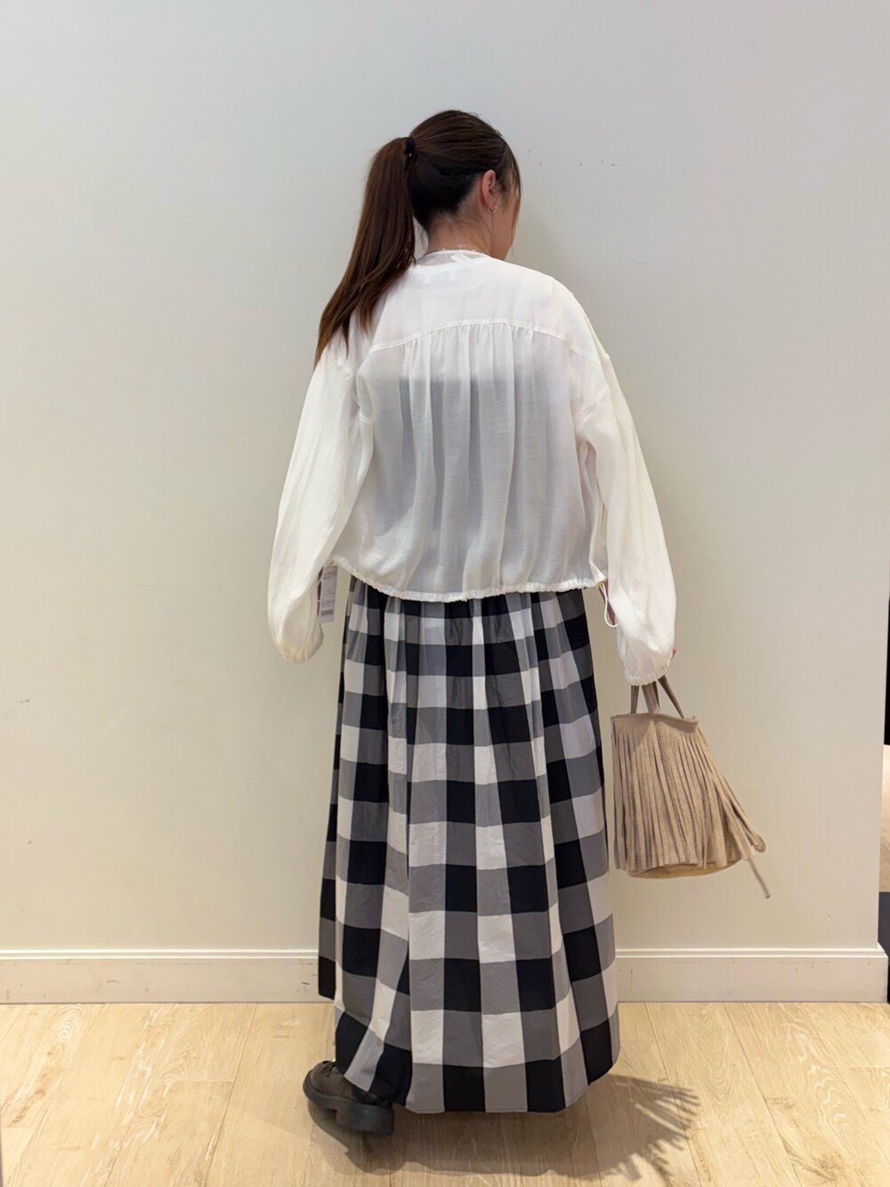 ベージュ系のショルダーバッグ、ブラック系のワンピース、ホワイト系のブルゾンを着用したレディースの春コーディネートの2枚目の写真