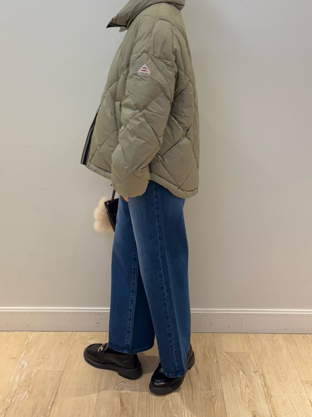 イエロー系のニット/セーター、ブラック系のショルダーバッグ、ブルー系のデニムパンツを着用したレディースの秋コーディネートの2枚目の写真