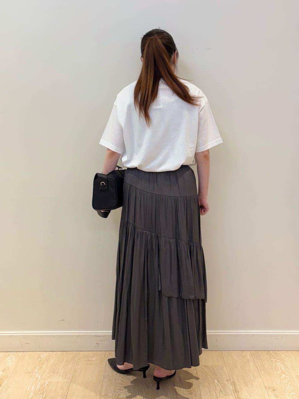 ブラック系のショルダーバッグ、グレー系のスカート、ホワイト系のTシャツ/カットソーを着用したレディースの夏コーディネートの3枚目の写真