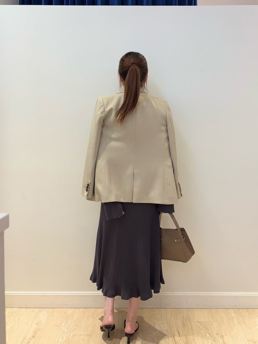 ベージュ系のショルダーバッグ、グレー系のワンピース、ベージュ系のテーラードジャケットを着用したレディースの冬コーディネートの3枚目の写真